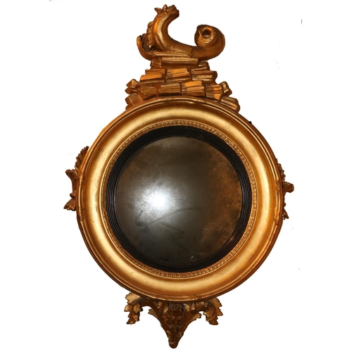 47 - A Regency period Convex Mirror, the carved giltwood frame crested with a stylized dolphin above leaf... 
