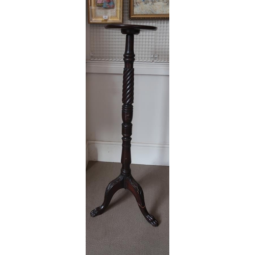 33 - A mahogany torcher raised on trefoil base terminating in lion paw feet, 125 cms high.