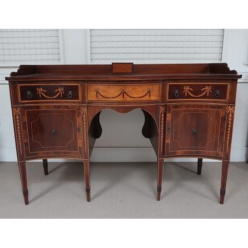 54 - A George III revival mahogany and satinwood serpentine sideboard, the frieze with three drawers deco... 