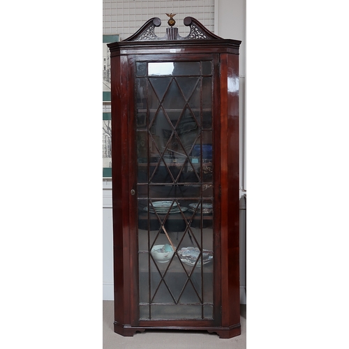 57 - A late Georgian mahogany corner cabinet, broken swan neck pediment above glazed door, raised on brac... 