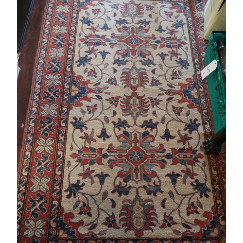 51 - A Kazak wool rug, the cream ground with overall design with multiple rust borders, 200 x 123 cms.