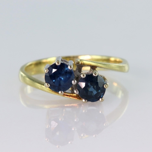 12 - 14ct yellow gold crossover style ring set with two round sapphires measuring approx. 4.5mm diameter,... 