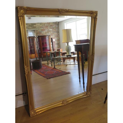 11 - An ornate gilt modern mirror, 131cm x 102cm, small chip to gilt