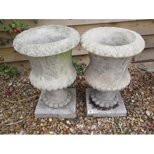 32 - A pair of stone effect urns on stands, 52cm tall x 35cm
