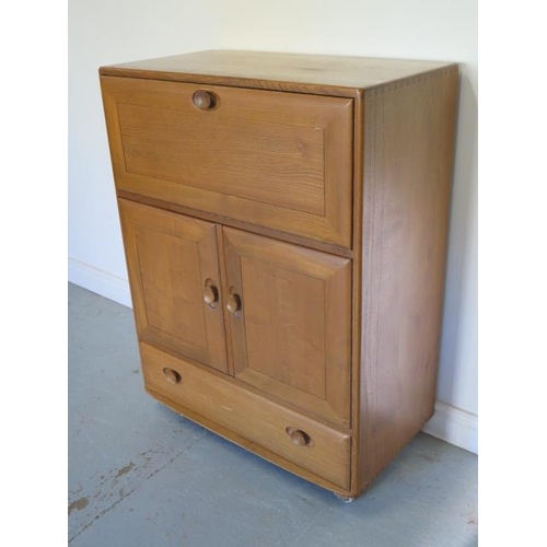 20 - An Ercol light elm cabinet with a drop front above two cupboard doors above a drawer on casters, 110... 