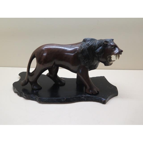 310 - A carved hardwood lion on stand, 15cm tall x 29cm long, in good condition