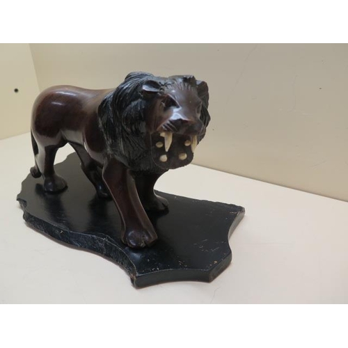 310 - A carved hardwood lion on stand, 15cm tall x 29cm long, in good condition