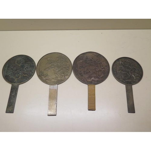 313 - Four Oriental bronze hand mirrors, largest 22cm tall