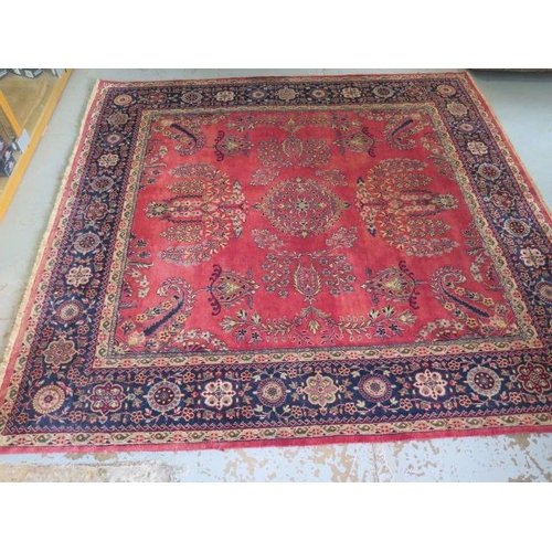 201 - A hand knotted woollen rug with a red field, some slight wear but no holes, 215cm x 203cm