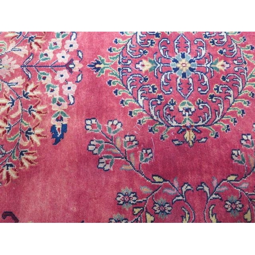 201 - A hand knotted woollen rug with a red field, some slight wear but no holes, 215cm x 203cm