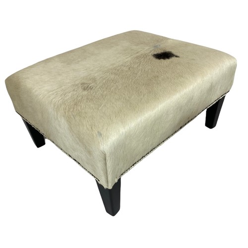 24 - COWHIDE FOOTSTOOLS, a pair, with ebonised supports, 40cm H x 76cm x 62cm. (2)