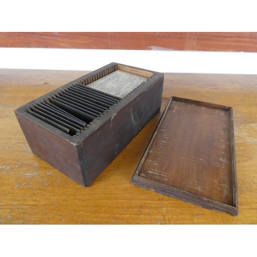 23 - A collection of antique glass slides in a wooden box.