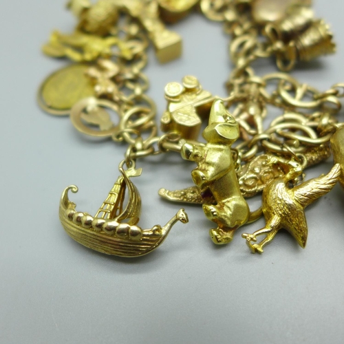 960 - A 9ct gold charm bracelet, twenty-one charms including a 14k Statue of Liberty, 81.6g