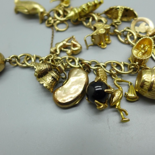 960 - A 9ct gold charm bracelet, twenty-one charms including a 14k Statue of Liberty, 81.6g