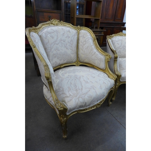 14 - A pair of French Louis XV style lady's and gentleman's giltwood and fabric upholstered fauteuil armc... 