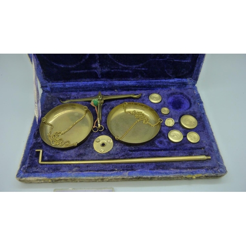 653 - A cased set of jeweller's scales and two coins, (scales lacking one weight)