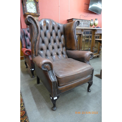 14 - A chestnut brown leather Chesterfield wingback armchair
