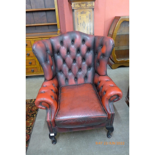 15 - An oxblood red leather Chesterfield wingback armchair