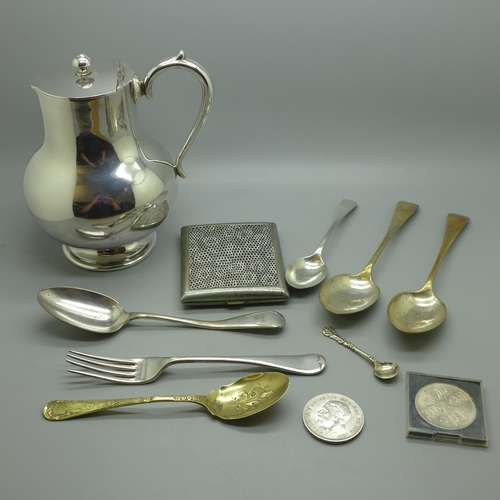 636 - Plated ware including a jug, flatware, a cigarette box, a silver spoon, 25g, and two crowns