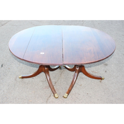 25 - Oval mahogany extending dining table with additional leaf, with brass claw feet