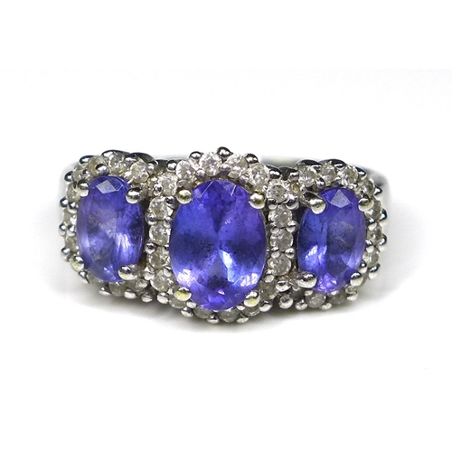 242 - An 18ct white gold, tanzanite and diamond ring, the three oval cut tanzanites surrounded by 40 diamo... 