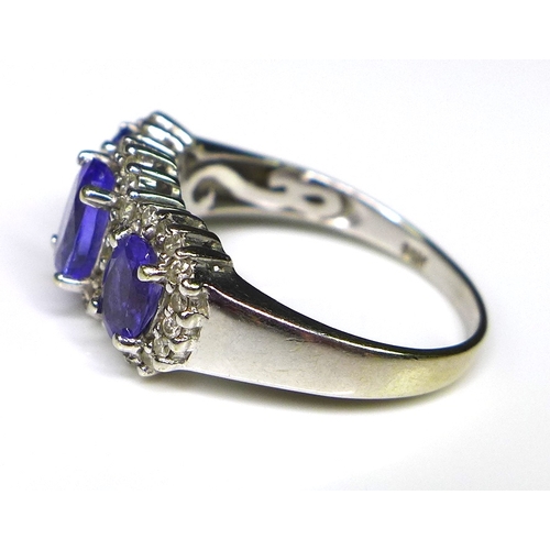 242 - An 18ct white gold, tanzanite and diamond ring, the three oval cut tanzanites surrounded by 40 diamo... 