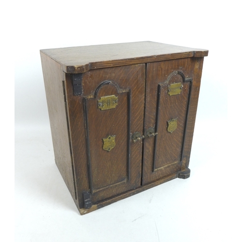 122 - A late Victorian smoker's cabinet, in the form of a safe with brass plaques to the twin doors, one e... 