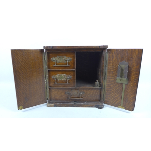 122 - A late Victorian smoker's cabinet, in the form of a safe with brass plaques to the twin doors, one e... 
