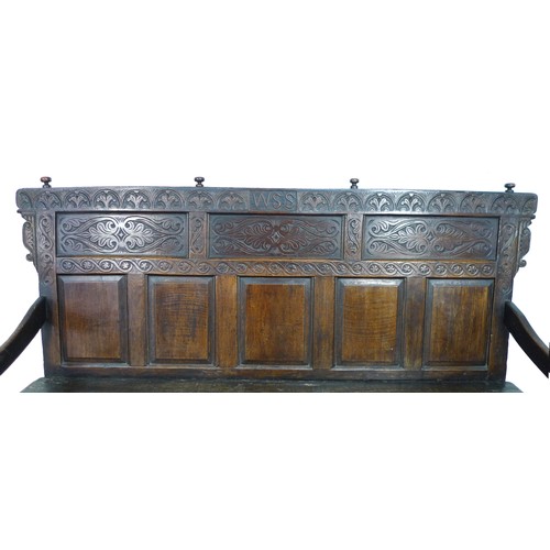 375 - A 17th century provincial oak settle, the rectangular back with a decorative frieze and three panels... 