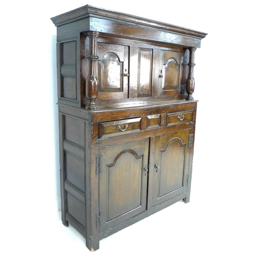 240 - An 18th century oak court cupboard, the cornice supported on two baluster columns, two small arched ... 