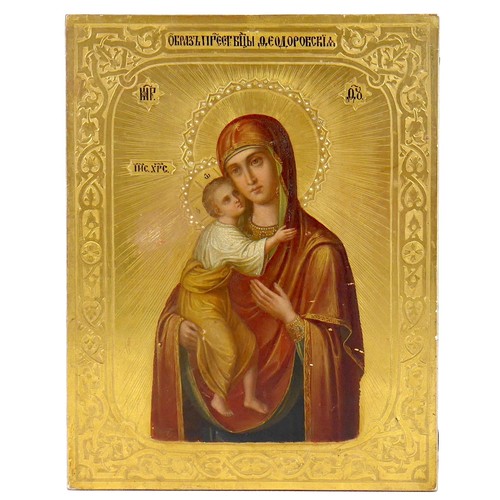 44 - An early 20th century Russian gilded and painted icon of the Holy Mother and Child, titled in black ... 