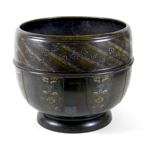 A Chinese bronze cloisonne enamel jardiniere, likely 19th century, decorated with a wide band of diagonal fan shaped motifs in white, green, red, and blue, scattered with blue flowers, above seven panels with floral designs, square 'signature' panel to the side with four characters against a turquoise ground, later inscribed by hand to base 'W.O. 215 .... A/VS/4', 42 by 36cm high, 8.44kg.
Provenance: owned by the current Vendors for approximately 70 years, and purported to have been purchased from the auction of house contents in 1948 from North Luffenham Hall, Rutland, erstwhile home of Elsie, Guy and Richard Fenwick.