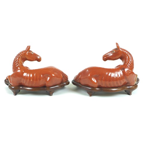 4 - A pair of Chinese porcelain sculptures of horses, both in a seated position with turned heads, in ru... 