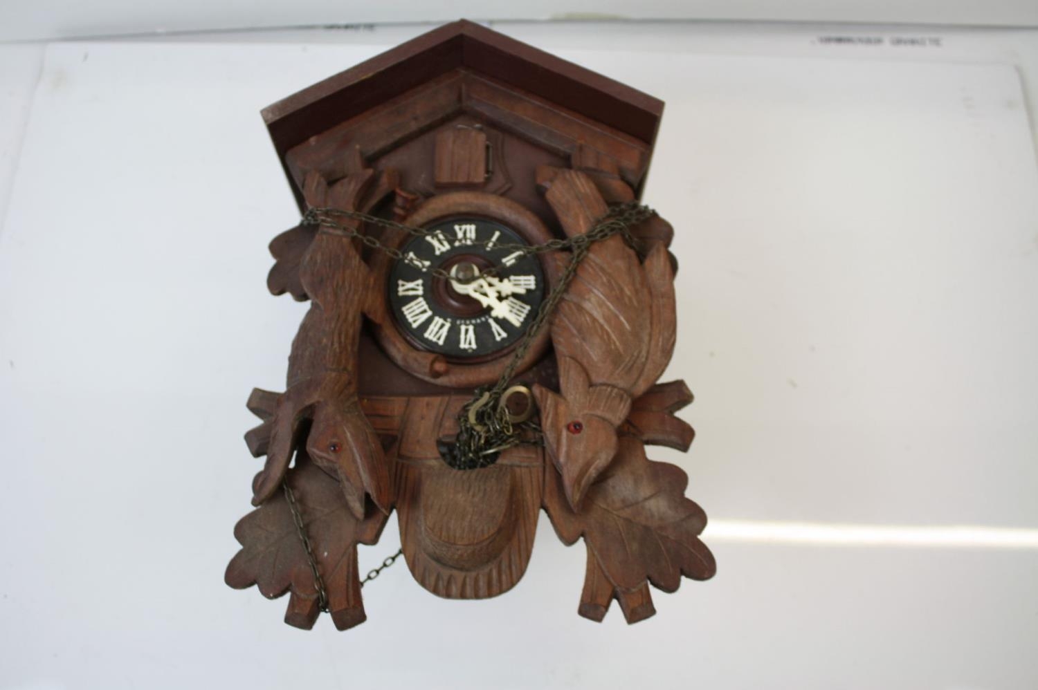 A vintage wooden cuckoo clock with Bird and Hare decoration to the front.