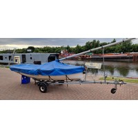 An Enterprise sailing dinghy, serial number 310, mould 10, sail number K16581, 4 meter/two person, blue sails dated 2001, no batons, fibreglass hull, marine ply top deck, launching trailer, road trailer, mast up/down cover, steel rigging, some shackles missing, rudder