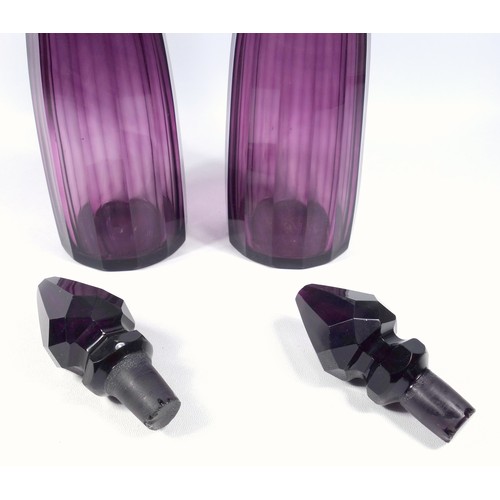 566 - A pair of Victorian amethyst glass decanters, with step cut and faceted decoration, H. 36 cm.