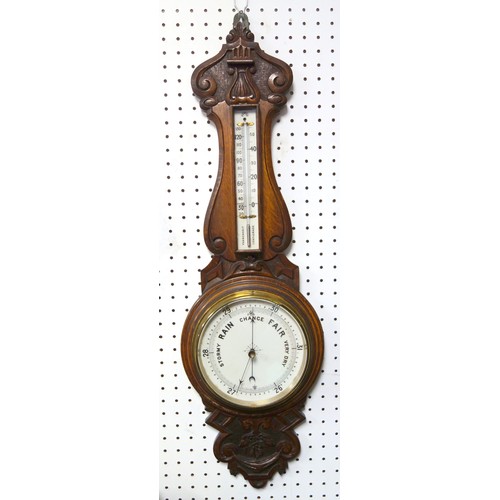 73 - An Edwardian carved oak aneroid barometer, with thermometer and circular dial, 88cm long