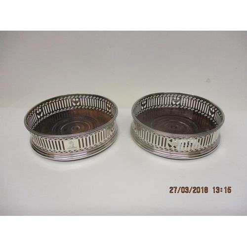 36 - A pair of George III silver bottle coasters with bead rim, urn and pierced sides on a stepped foot a... 