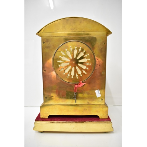 6 - An early 20th century brass mantle clock on a gilded treen stand, the arched top case with floral cl... 