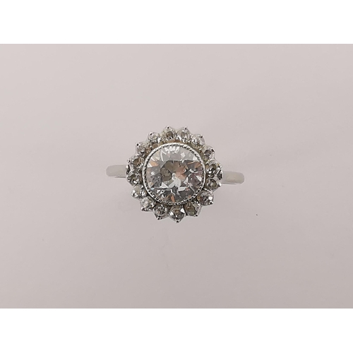 An 18ct white gold ring set with central diamond approximately 1.5ct surrounded by 16 brilliant cut diamonds, size M