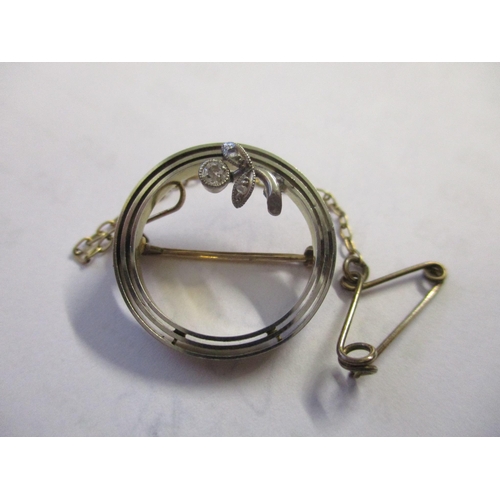 2 - A platinum and gold coloured brooch of circular form set with a diamond, 3g
Location: C