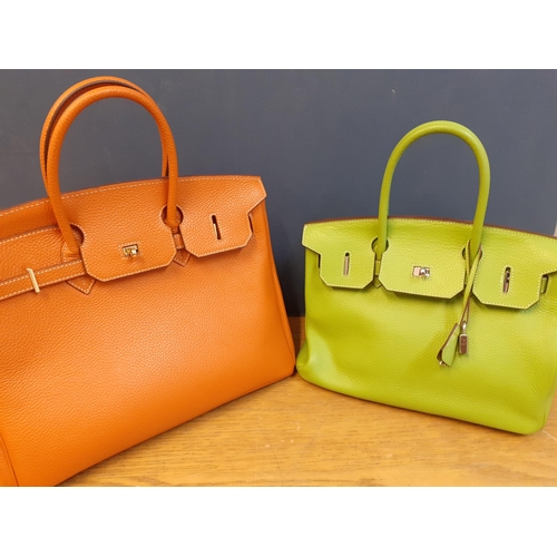 2 - Two modern leather handbags in the style of the Birkin bag, one in orange and the other in lime gree... 