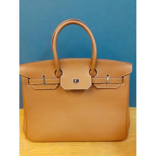 3 - Two modern leather handbags, one in the Birkin style in mid brown with a padlock and the other in na... 