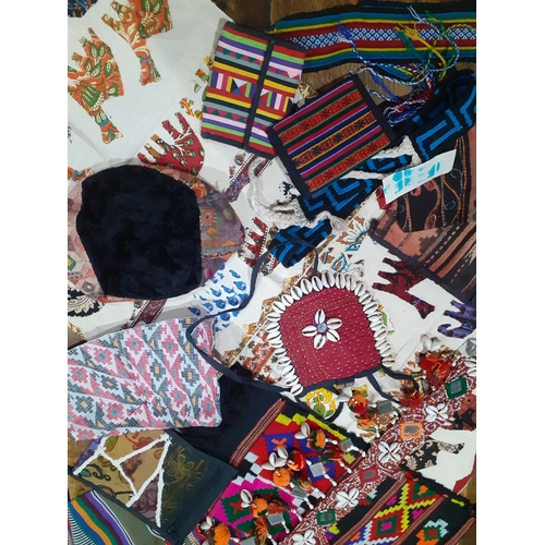 34 - A quantity of African textiles to include cushion covers, panels, belts, hats, purses and cloth bags... 