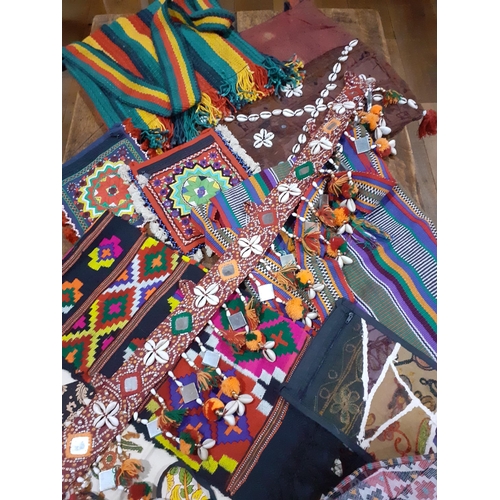 34 - A quantity of African textiles to include cushion covers, panels, belts, hats, purses and cloth bags... 