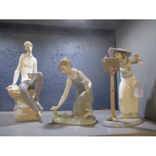 A group of three Lladro porcelain figurines to include a seated young man reading a book, another of a girl picking flowers, and another of a woman singing with a bird perched on a music stand 
Location: 5.1