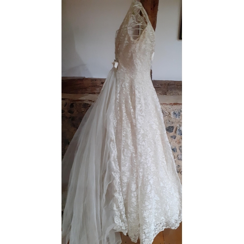 53 - A post 1950's cream lace sleeveless wedding dress with silver coloured thread detail and attached ne... 