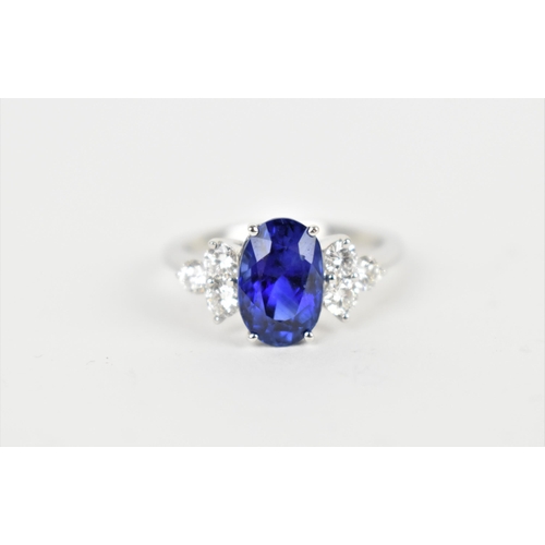 An 18ct white gold, diamond and sapphire dress ring, with central oval cut sapphire in a four claw setting, flanked with three brilliant cut diamonds either side, the sapphire roughly 1cm long x 0.65mm wide, size N 1/2