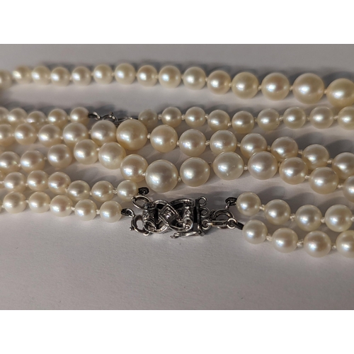12 - A graduated pearl necklace having 9ct white gold spring rings and a white metal clasp inset with thr... 