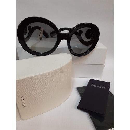 Prada- A pair of new and black framed sunglasses with original American retail tag ($300) and branded box, having oversized and circular 1950's style lenses and swirls to the side arms
Location: BWR